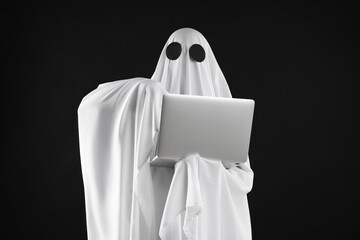 Creepy ghost. Person in white sheet with laptop on black background