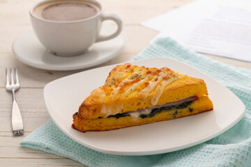 Croque monsieur with ham and spinach on a white square serving plate, served with a cup of coffee for breakfast or coffee break.