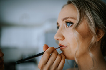 Riga, Latvia - January 20, 2024 - a close-up of a woman having makeup applied to her lips with a...