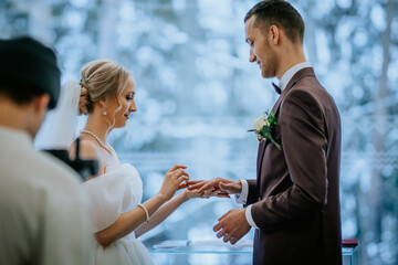 Riga, Latvia - January 20, 2024 - A bride and groom exchange rings during a wedding ceremony with a...