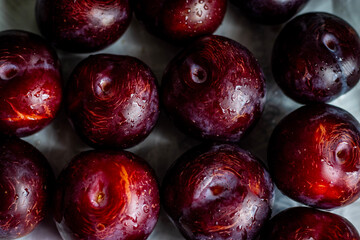 Many delicious ripe plums as background, closeup. Fresh plum with water splashes and drops.