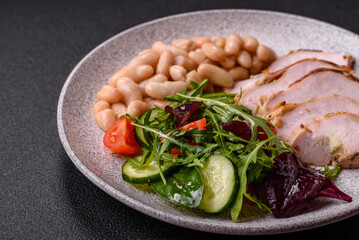 Delicious dietary salad with arugula, cucumber and cherry tomatoes and chicken breast slices