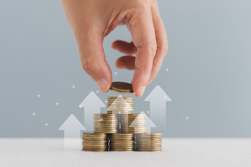 Hand arranged stack of coins, in soft focus, with up arrow  for financial banking increase interest...
