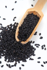 Black sesame seeds with wooden scoop isolated on white with copy space