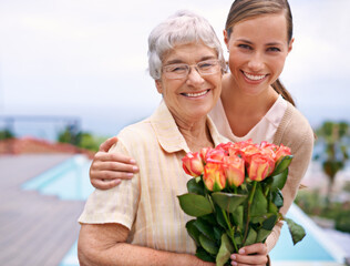 Senior woman, daughter and portrait with flowers, hug and care for love, bonding and reunion at...