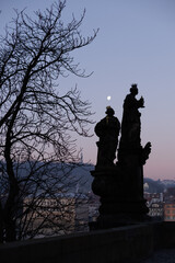 A couple of statues are seated on top of the iconic Charles Bridge, creating a historic and architectural scene, sunrise