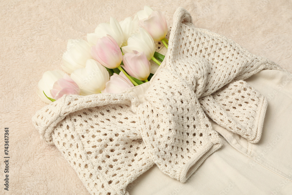 Sticker Beige shorts, sweater and flowers on beige background, close up