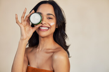 Hispanic woman holding beauty cream jar while smiling