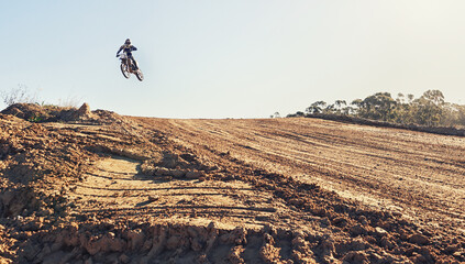 Person, jump and dirt track of professional motorcyclist in the air for trick, stunt or race on...