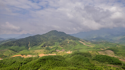 Expansive view of lush green mountains under a cloudy sky, ideal for nature-themed backgrounds with ample copy space, Earth day concept