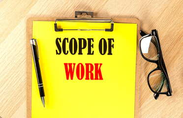SCOPE OF WORK text on a yellow paper on wooden background
