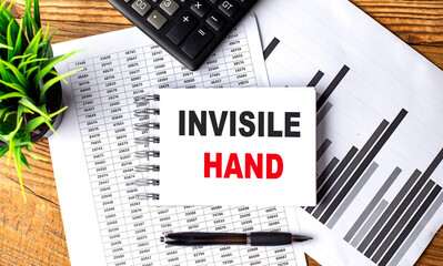 INVISIBLE HAND text on a notebook with chart and calculator