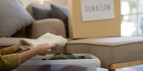 Donation, asian young woman sitting pack object at home, putting on stuff into donate box with...