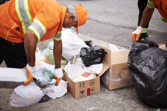 Men, garbage and trash collection on street for waste management in city, pollution and recycling plastic. Team, uniform and sanitation service with rubbish, boxes or cleaning junk for maintenance