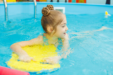 A little girl is swimming in the pool with a coach. Teaching children to swim. Children's swimming school