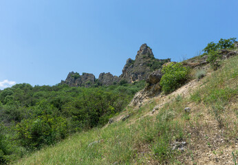 The ruins of a medieval castle on top of a huge rock. Stone walls are a continuation and are...