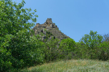 The ruins of a medieval castle on top of a huge rock. Stone walls are a continuation and are...