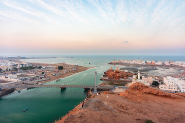 Panoramic view on west and east part of the Sur city in golden hour. Al Ayjah Bridge on foreground, Sur Province, Sur, Oman