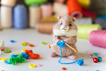 Fototapeta na wymiar Knitted hamster toy with yarn and knitting accessories