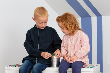 Two young children a girl and a boy having fun with paintbrushes
