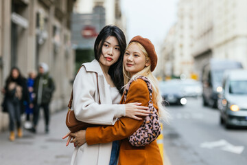 Lesbian couple hugging each other while standing on the street.