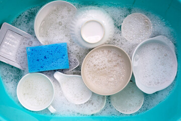 Fototapeta na wymiar Plates and bowl soaking in foam of dishwashing liquid