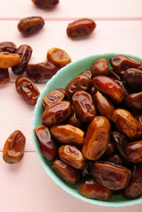 Fresh dates in mint bowl on pink background. Vertical photo