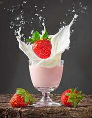 Splash of a strawberry falling into the glass with cream, on a black background - 743703905
