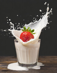 Splash of a strawberry falling into the glass with cream, on a black background - 743703950