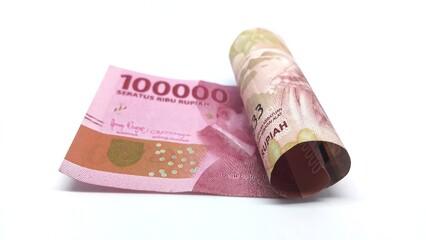 a roll of Indonesian banknotes worth IDR 100,000. Indonesian currency rupiah isolated on white background