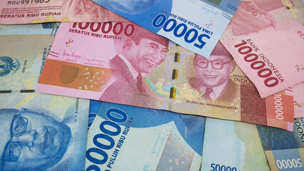 Indonesian currency worth IDR 100,000 and IDR 50,000 fills the frame. Backgrond concept