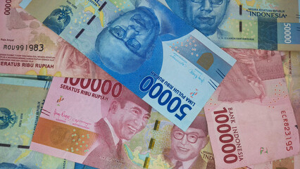 Indonesian currency worth IDR 100,000 and IDR 50,000 fills the frame. Backgrond concept
