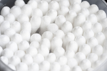 Macro view of white cotton ear cleaning buds arranged in black backgroud nicely in a container