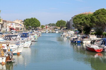 The canal of Beaucaire, Gard, Occitanie, France. Downtown, spring, perfect blue sky. Many boats, water, French flags.