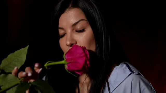 loving man giving red rose to beautiful brunette woman sitting on bed in bedroom, passionate lovers
