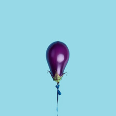 An eggplant in the style of purple balloon isolated on the pastel blue background.  Birthday vegan conceptual artwork wallpaper