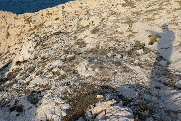 Shadow of the photographer on the white limestone surface of rocks. Marseille, Les Goudes, France.