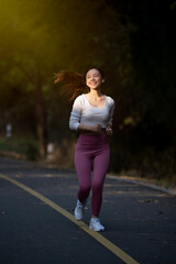 Cheerful woman enjoys jogging on the street in the warm morning sun.