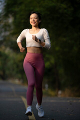 Cheerful woman enjoys jogging on the street in the warm morning sun.