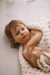 Little baby wrapped in a knitted blanket at home. Parental protection, care and love