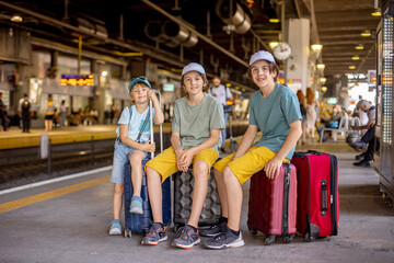 Fototapeta na wymiar Children, boy brothers holding suitcases, travelin, waiting at trainstation to go to the airport