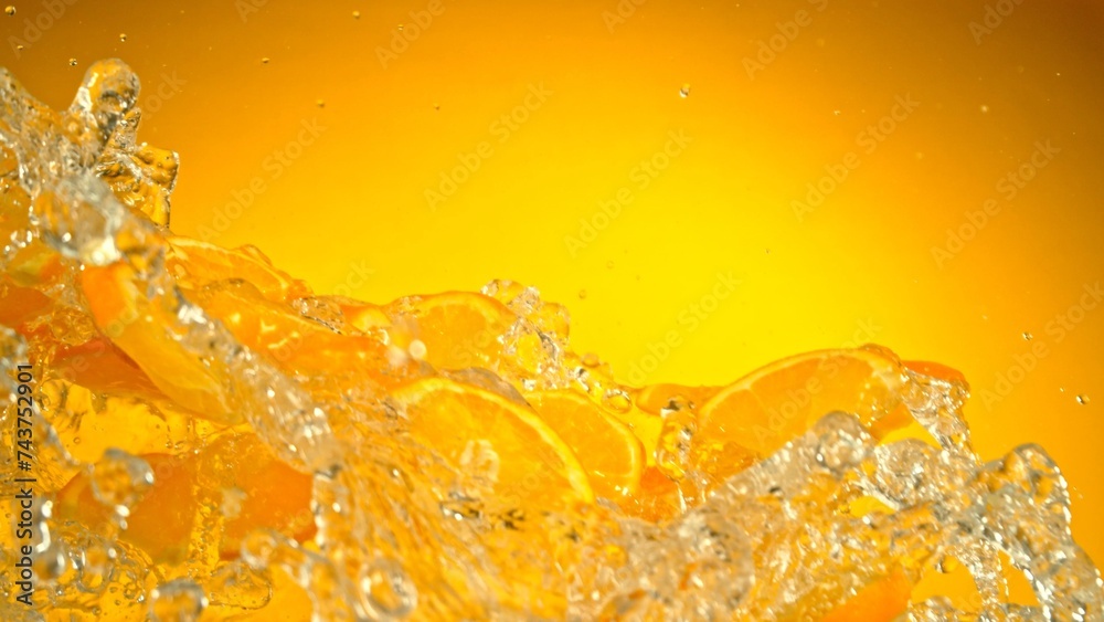 Poster freeze motion of flying slices of oranges with splashing water.