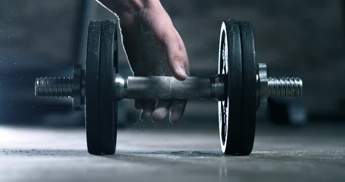 Super slow motion macro of male athlete hands with talc is doing workout by lifting weights of barbell to maintain healthy lifestyle and bodybuilding fitness goals in a gym at 1000 fps.