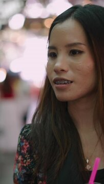 An Asian woman with orthodontics in a marketplace