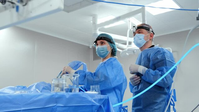 A team of doctors performs a laparoscopic surgery in the operating room while monitoring the procedure on a screen.