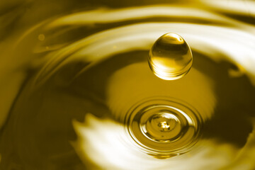 Splash of golden oily liquid with drop as background, closeup. Space for text