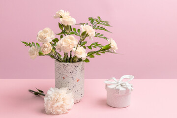 Bouquet of carnations in a vase with a gift box.