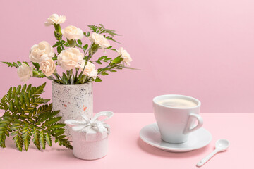 Bouquet of carnations in a vase with a gift box and a cup of coffee.