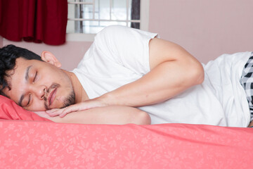 Obraz na płótnie Canvas an asian man is sleeping on a bed, side view