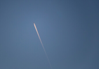 Airplane in the blue sky with white trace of the plane copy space